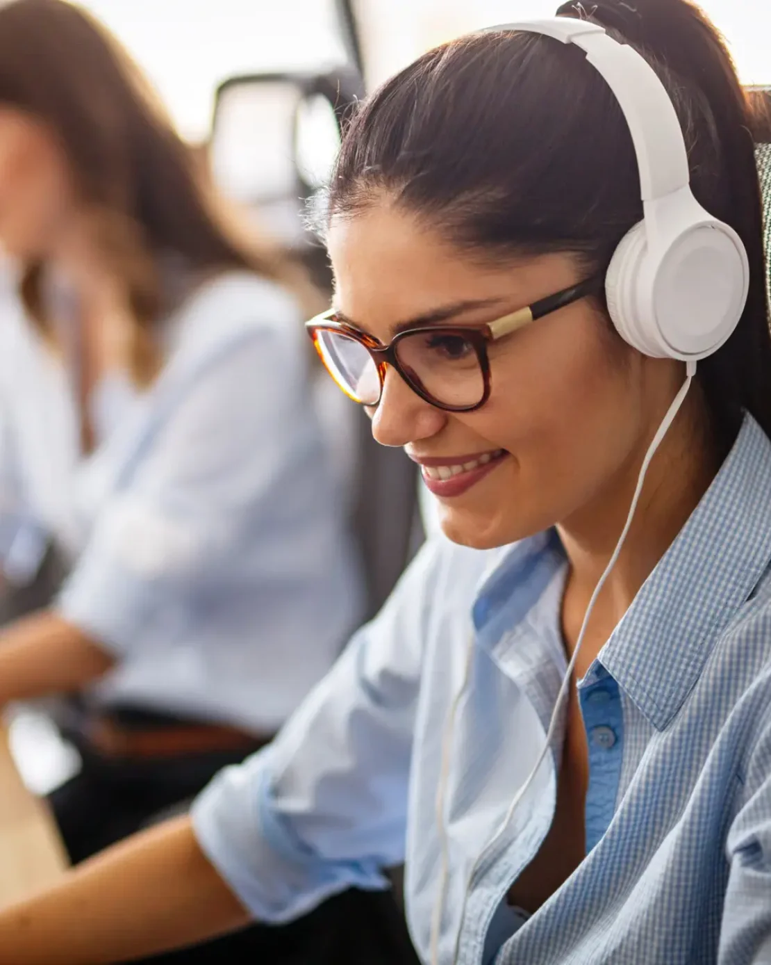 Friendly young female helpline operator with headphones in call center